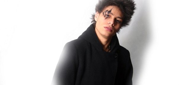 Young person with dark coat and hairstyle.
