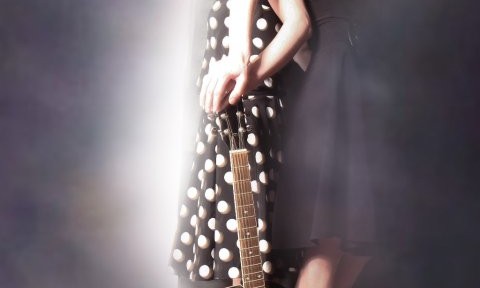 Two women posing with a guitar.
