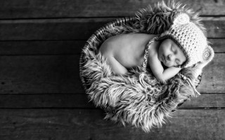 Sleeping baby in basket with knitted hat.