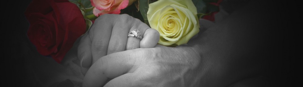 Hands with rings holding colorful roses.